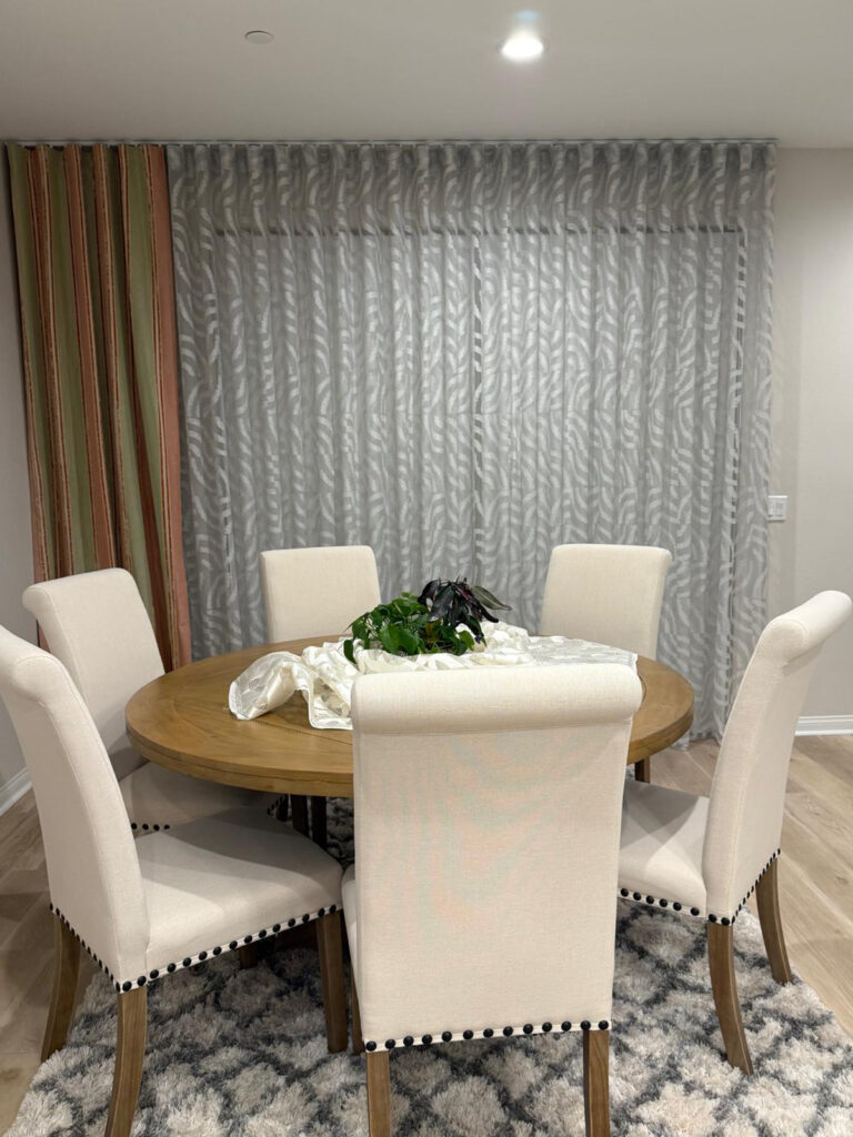 Custom curtains by Wardeh USA create an elegant backdrop behind a modern dining area