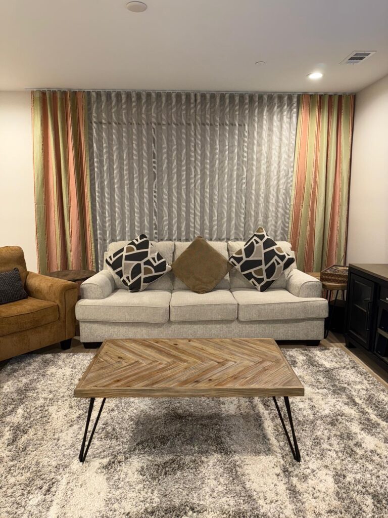Custom blinds by Wardeh USA create an elegant backdrop behind a modern sofa and herringbone coffee table