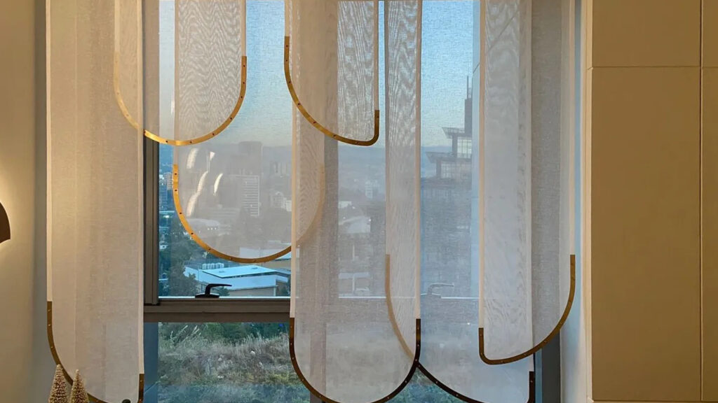 Closeup of sheer curtains with a striking gold metal edge